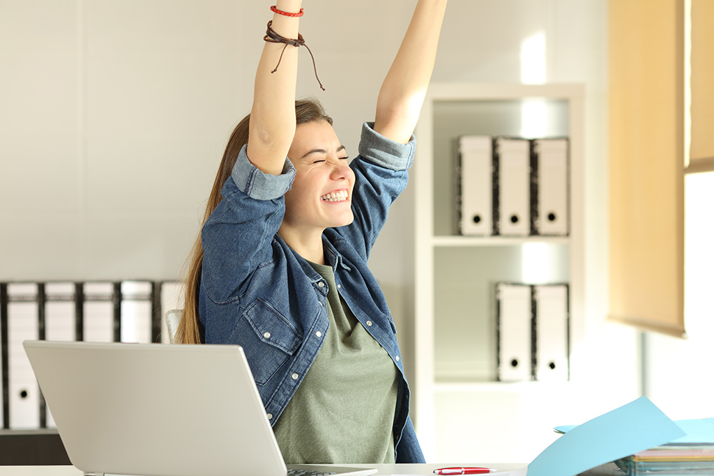 Satisfied intern raising arms at office joie au travail